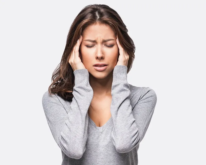 Woman holding head in discomfort — indicating TMJ or headache pain