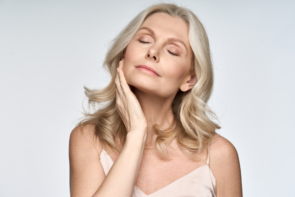 woman with eyes closed with her head tilted holding her jaw with a slight smile